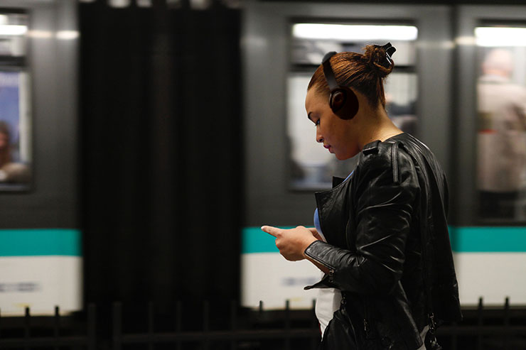 地下鉄のホームでヘッドホンを装着している女性の画像