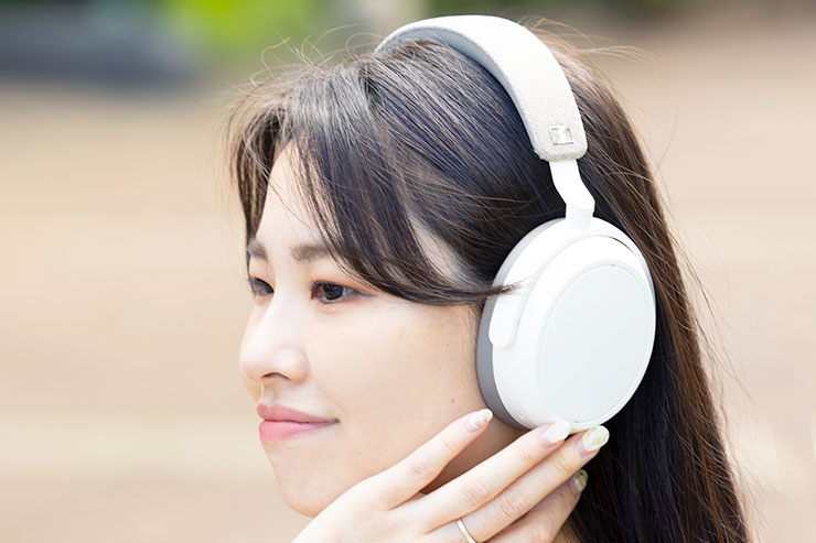 ワイヤレスヘッドホンを装着して操作する女性の画像